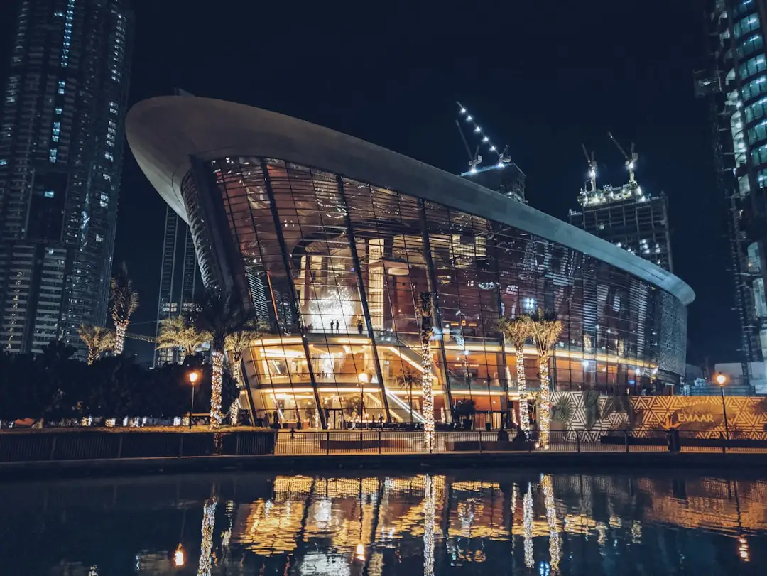 gray curtain wall building reflecting on body of water at night — Photo by Max Bovkun on Unsplash