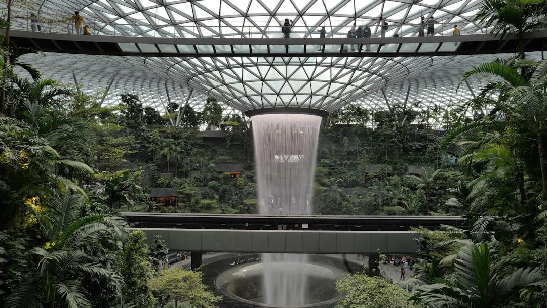 Indoor waterfall with lush green plants and modern architecture — Photo by Francesca Perez on Unsplash