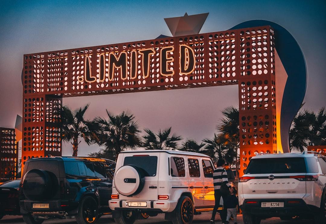 Cars parked under a large illuminated sign — Photo by Luan Fonseca on Unsplash
