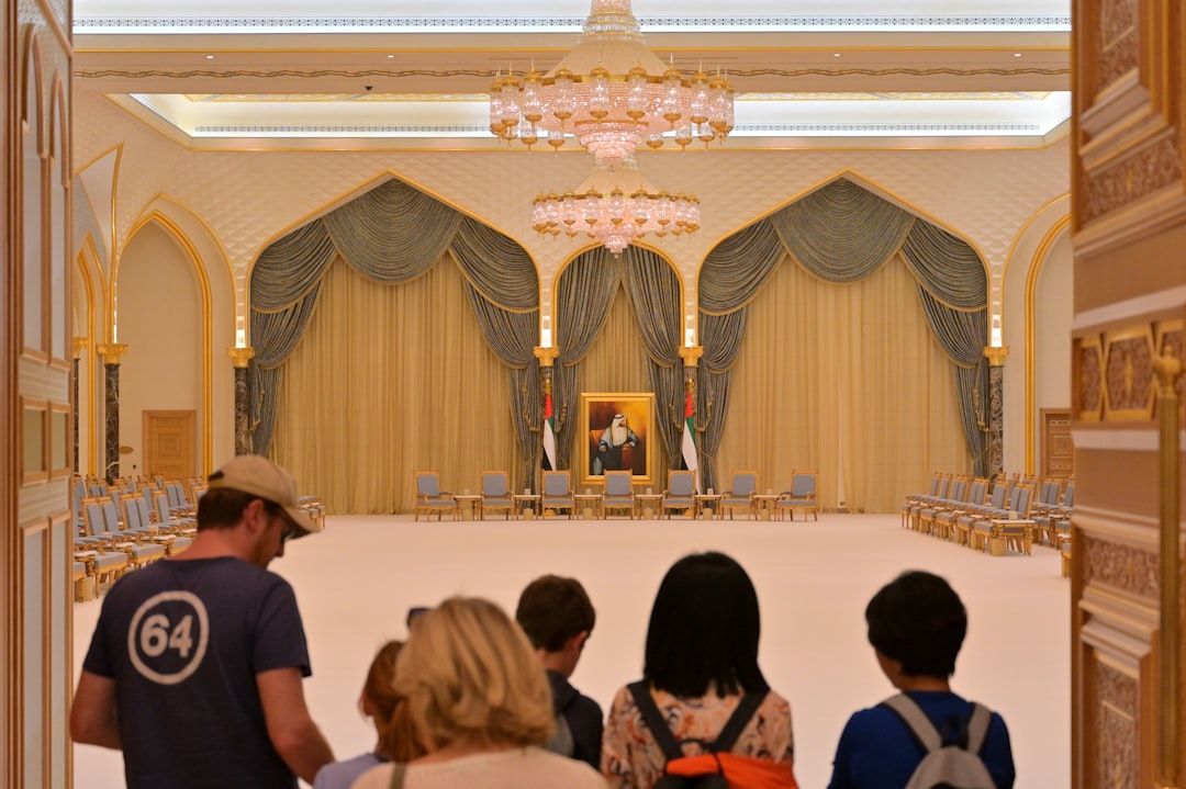 Tourists view a grand hall with a portrait and portrait. — Photo by Po-Hsuan Huang on Unsplash