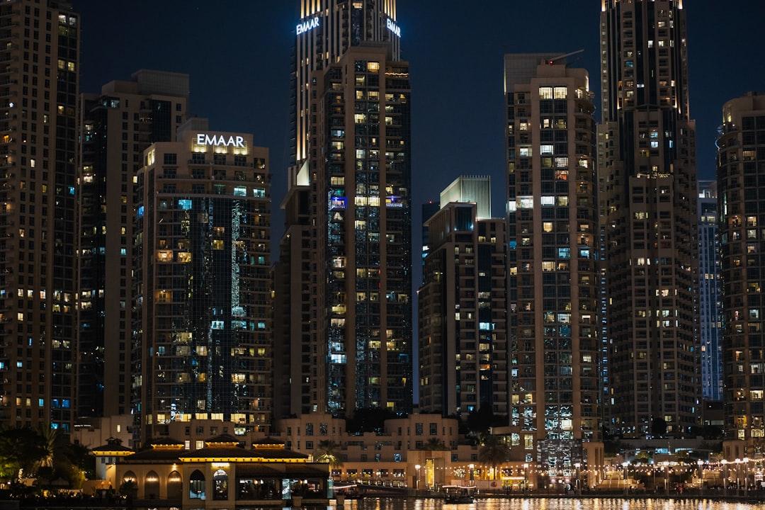 A city skyline at night with a boat in the water — Photo by Usman Yousaf on Unsplash