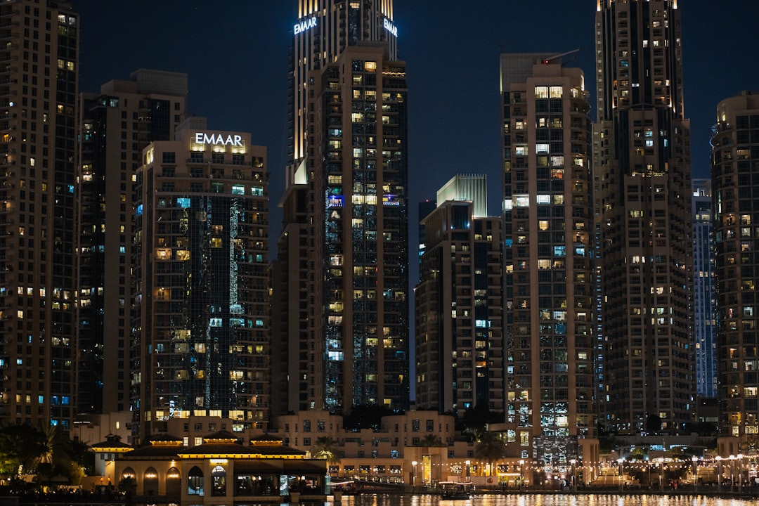 A city skyline at night with a boat in the water — Photo by Usman Yousaf on Unsplash