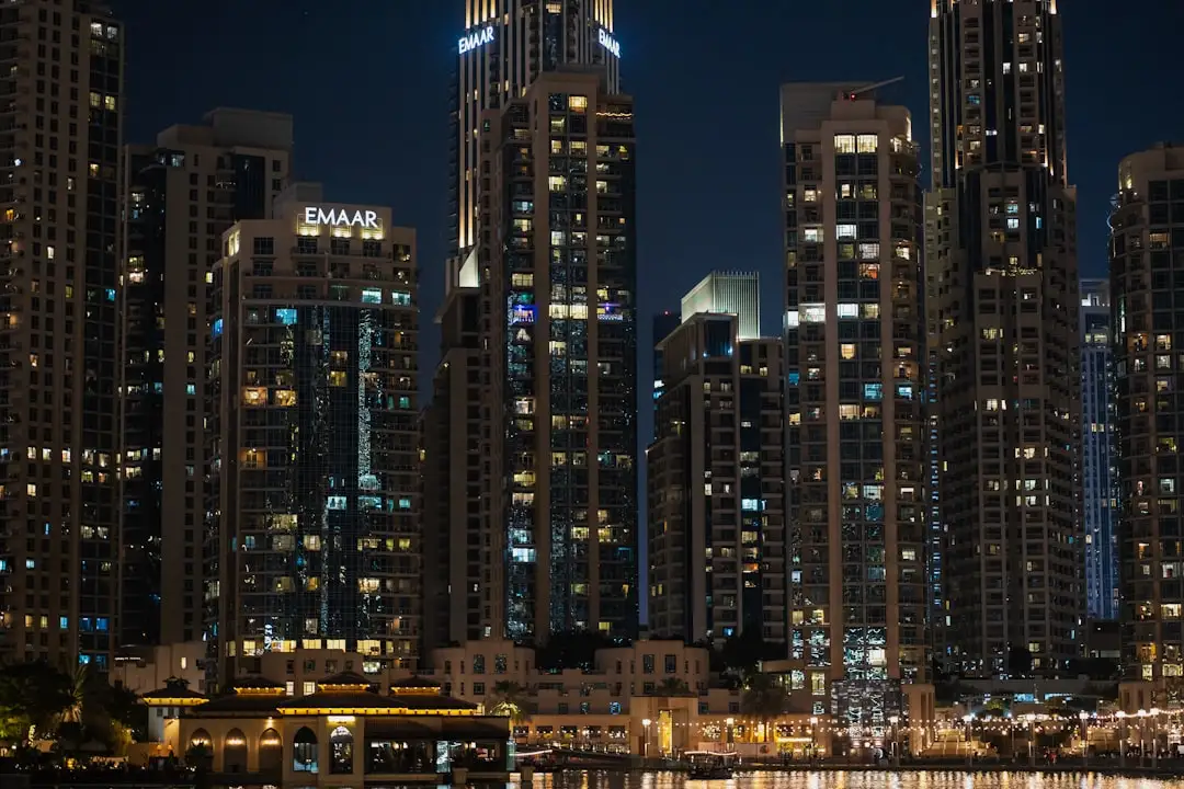 A city skyline at night with a boat in the water — Photo by Usman Yousaf on Unsplash