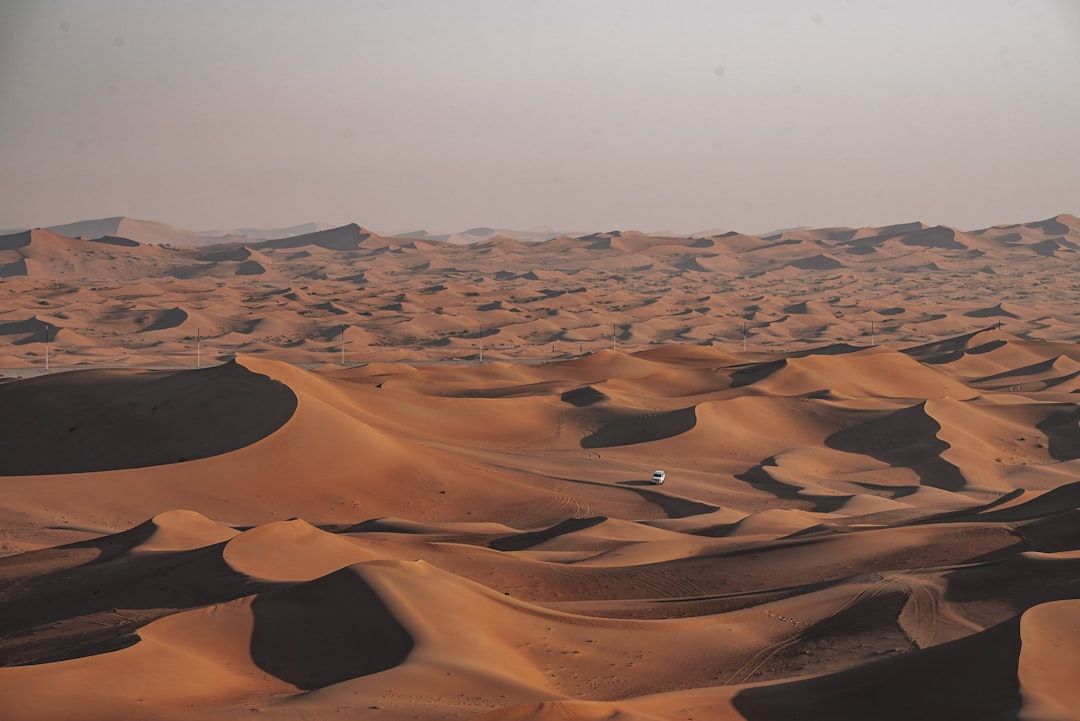 Vast desert sand dunes under a hazy sky — Photo by Nejc Soklič on Unsplash