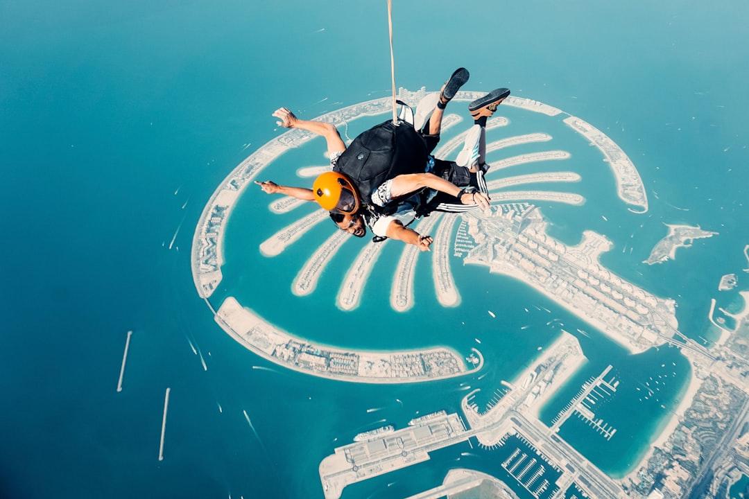 a man flying through the air while riding a parachute — Photo by ihjaaz manarikk on Unsplash