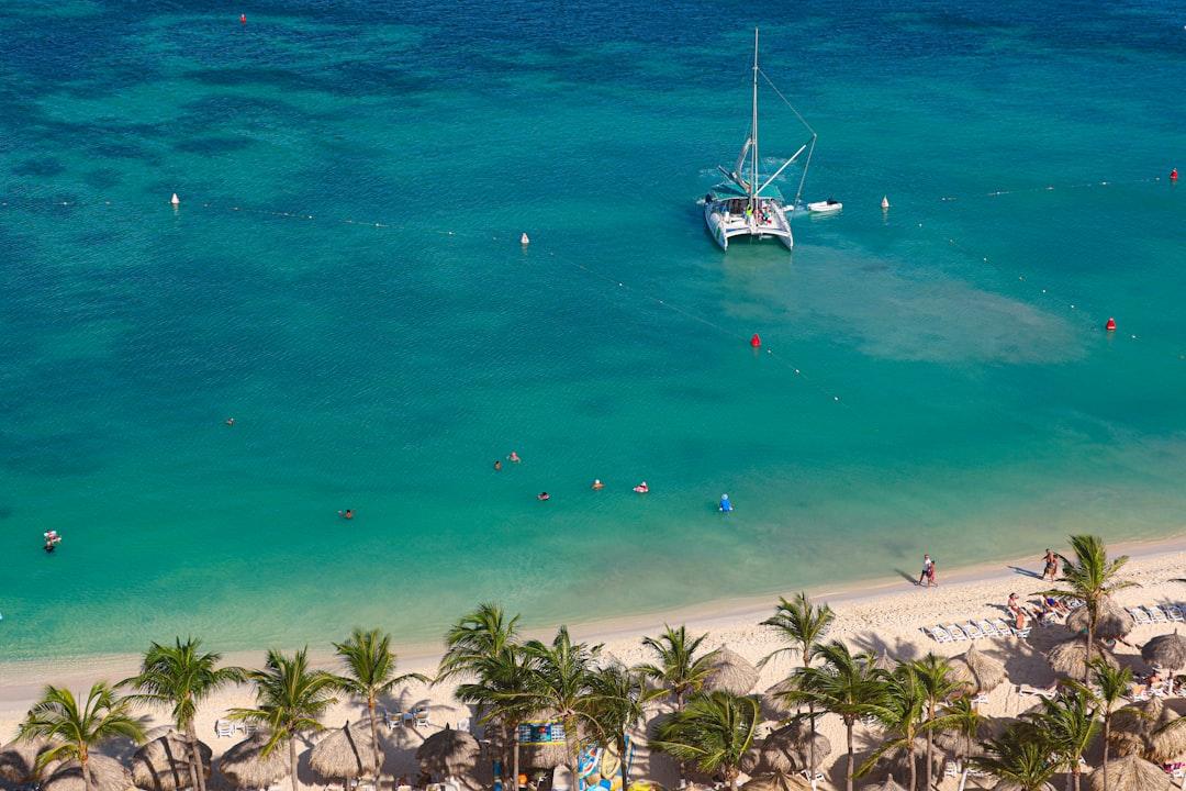 Catamaran sailing in clear turquoise ocean water near beach. — Photo by Meg von Haartman on Unsplash