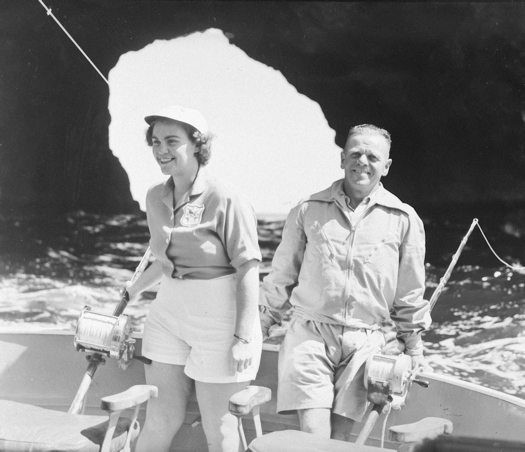 Couple fishing on a boat near a cave — Photo by Auckland War Memorial Museum Tāmaki Paenga Hira on Unsplash